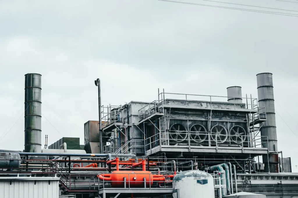 Industrial factory with metal pipes and special equipment surrounded with fences located against cloudy sky on street with po
