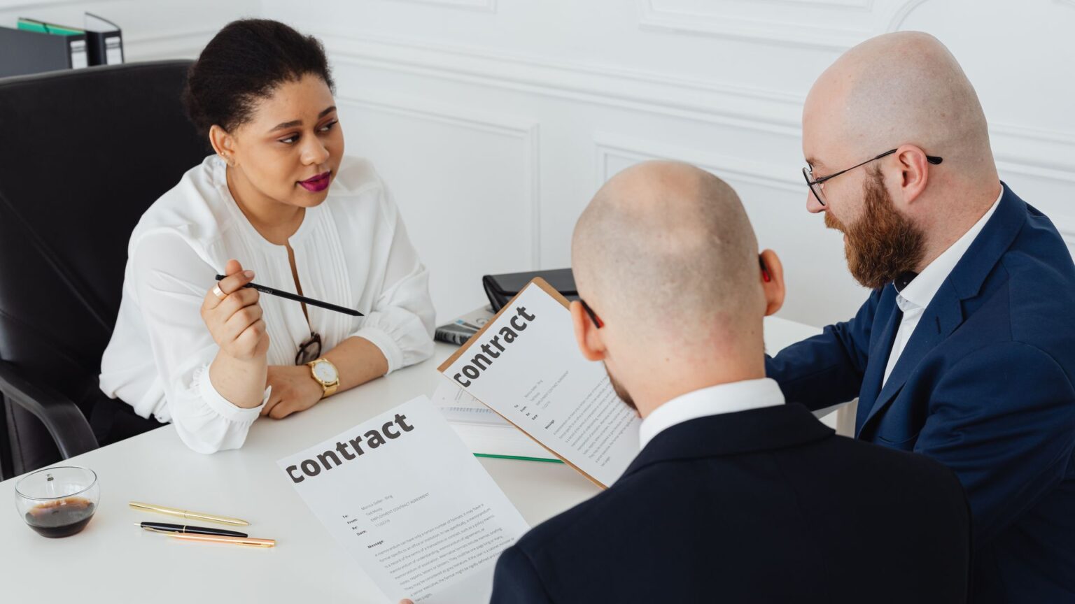 Lawyers talk through a contract with a client at an office desk, illustrating culturally Aware Negotiation Strategies for International Business Disputes